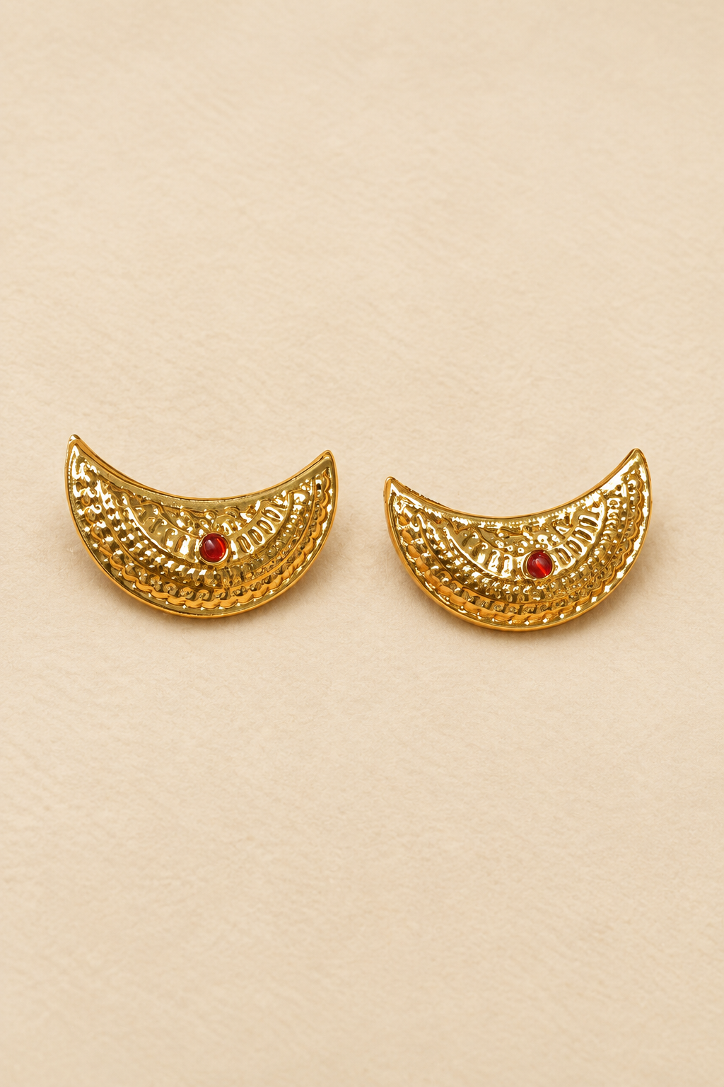 Gold crescent earrings on a warm ivory background