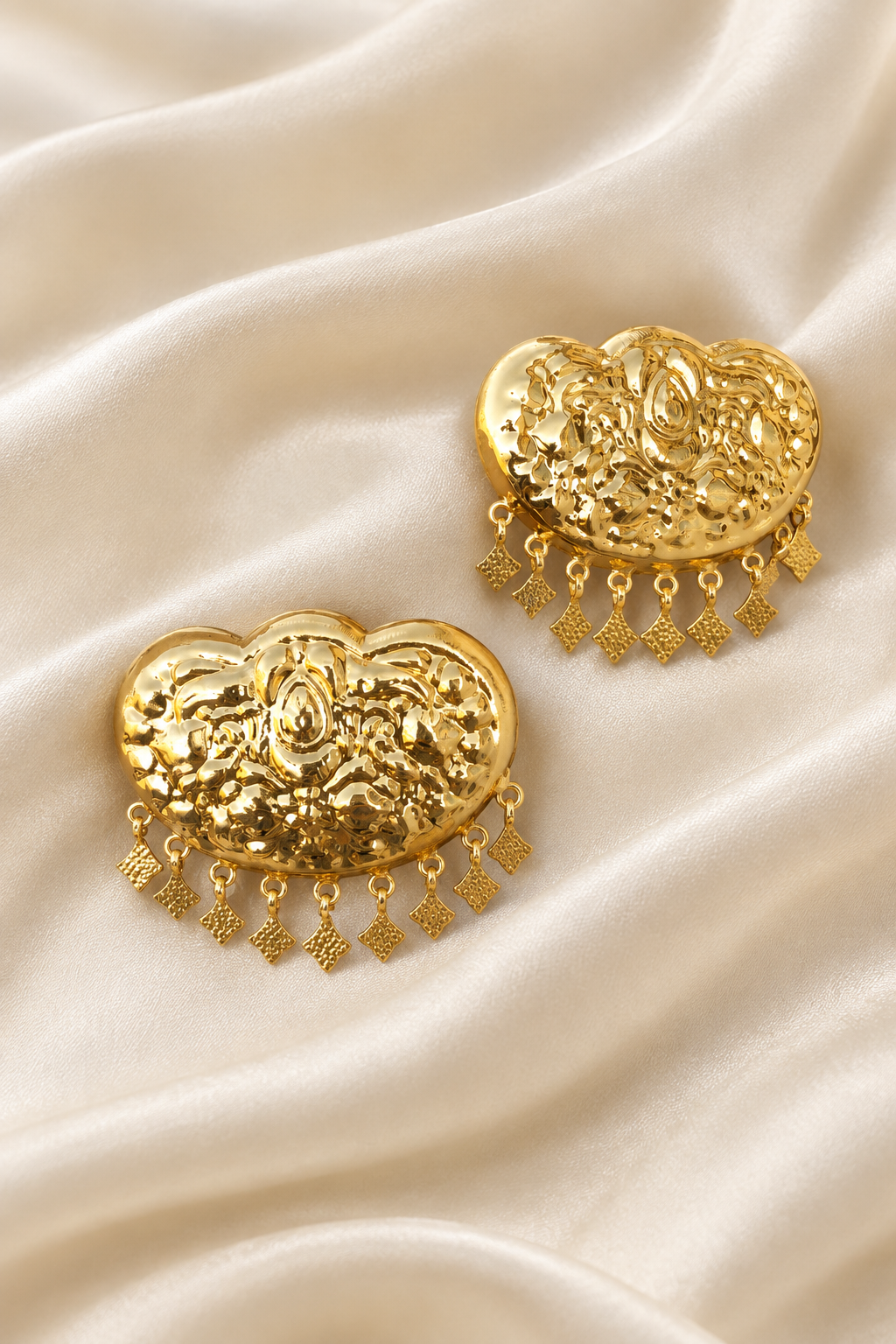 Gold earrings on an elegant ivory silk background