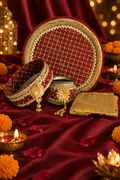 Karwa Chauth thali set on festive maroon background with diyas